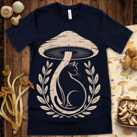 Illustration of a black cat sitting beneath a large vintage mushroom, framed by botanical laurels on a t-shirt design